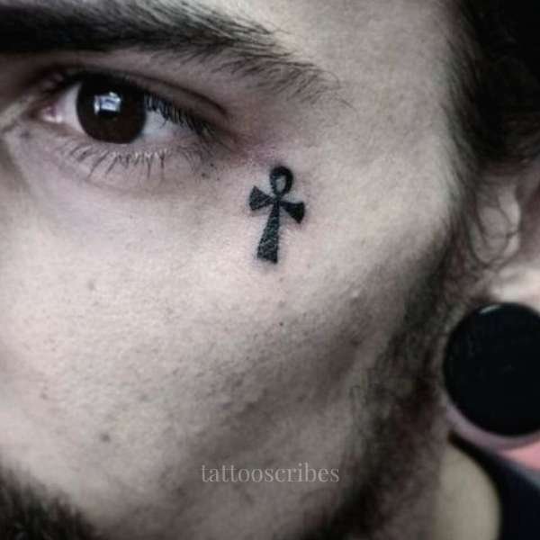 cross tattoo under the eye meaning